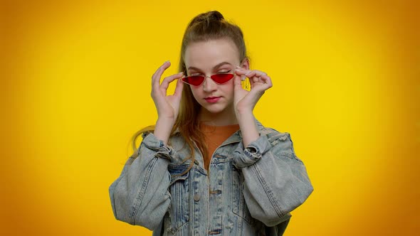 Seductive Cheerful Stylish Girl in Denim Jacket Wearing Sunglasses Charming Smile on Yellow Wall alt