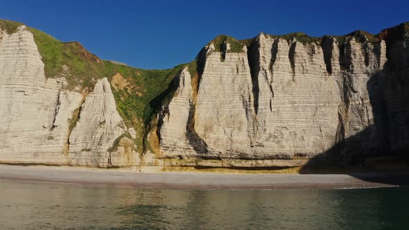 Picturesque Striped Rocks with Green Grass on Top Stretch Along the Sea Coast alt