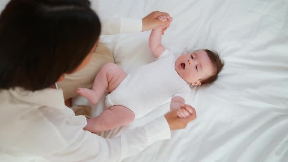 Mom Plays with Her Baby on the Bed