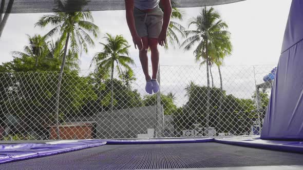 Young Sporty Man Is Making Extremal Tricks Jumping on Trampoline