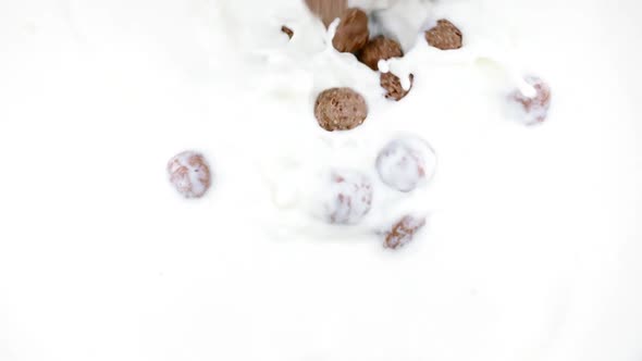 Chocolate Corn Cereal Balls Falling Into Organic Milk in Slow Motion