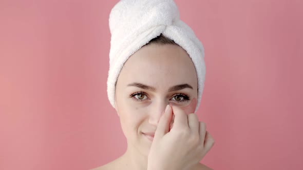 Plesant nude girl applying collagen eye masks on face in front of a mirror. alt