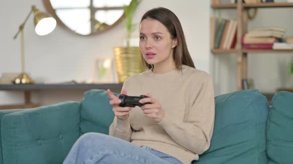 Young Woman Having Loss on Video Game on Sofa alt