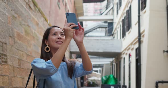 Woman tourist visit Hong Kong city and take photo on phone alt