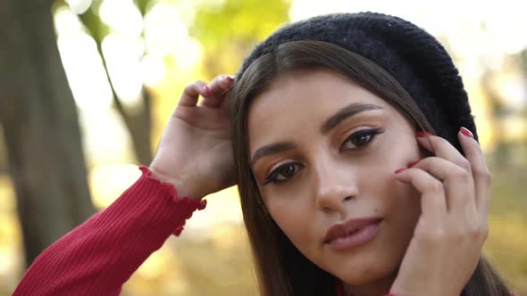 Close Portrait of Girl in a Cap Posing and Flirting at Camera in a Park alt