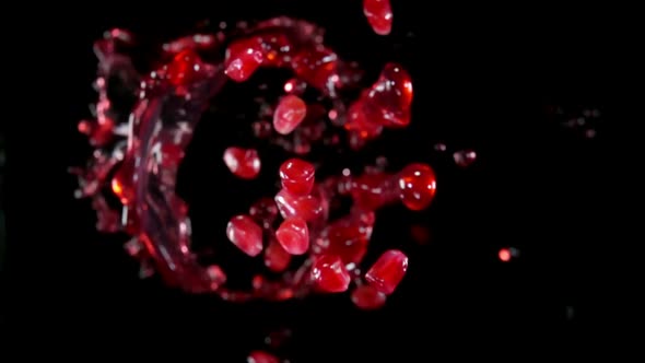 Pomegranate Grains are Bouncing Up with Splashes of Juice on a Black Background alt