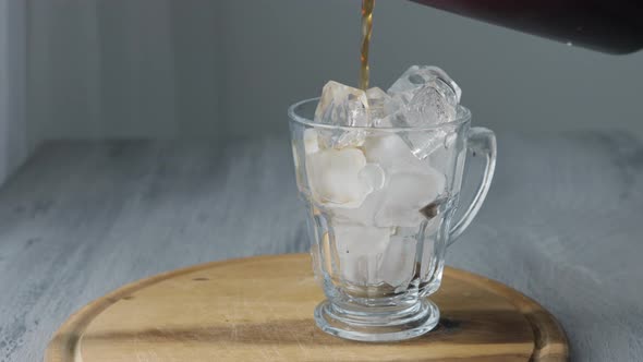 Pouring Cold Brewed Coffee over Ice. Cold coffee drink glass with ice and milk. Copy space.