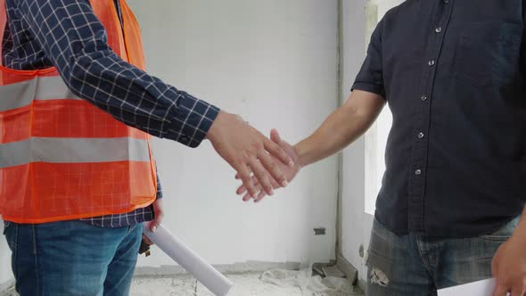 Engineer handshaking with the construction site owner in the construction site.