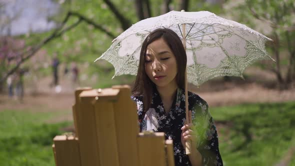 Charming Smiling Confident Asian Painter Painting in Spring Sunny Park Smiling alt