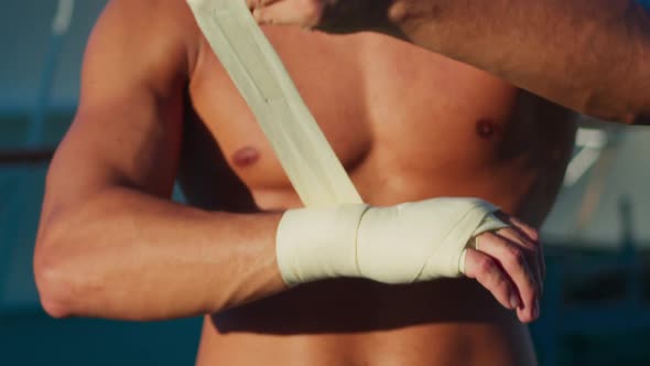 Sports Man with Naked Torso Puts on Hands Wraps to Exercise Box Workout