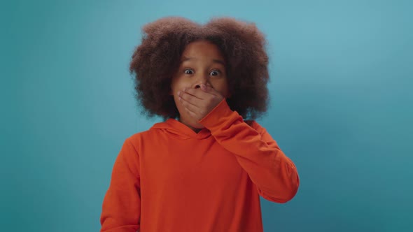 Shocked kid opening mouth and closing it with hand alt