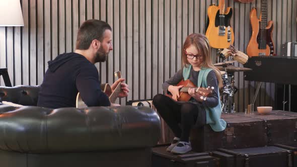 Dad Teaching Guitar and Ukulele to His Daughter
