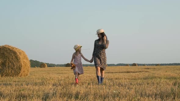 Little Girl with Mother Walk in Harvested Field alt