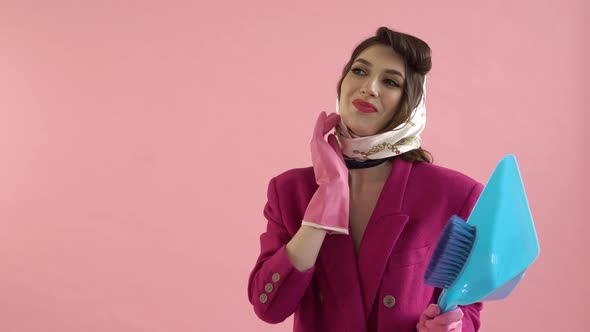 A Woman Wearing Rubber Gloves is Holding a Plastic Dustpan and a Cleaning Brush