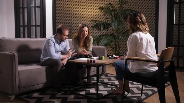 Couple Talking To Counselor Looking at Drawing alt