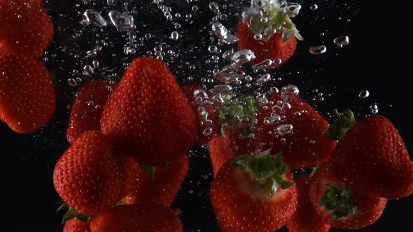Ripe Strawberry Falls Into the Water on a Black Background