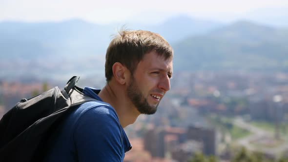 Male Tourist Looking Over Big City, Covering Eyes with Hand Against Sun, Travel alt