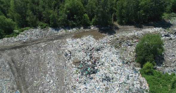 Aerial top view of Illegal garbage dump in the middle of the green forest.  alt