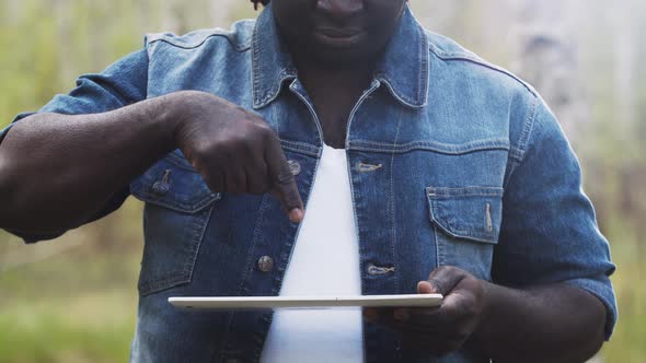 An African Man Using the Tablet in the Forest. Wireless or Future Technology Concept. alt