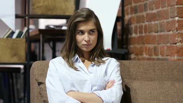 Frustrated Upset Girl Sitting on Sofa in Loft Office alt