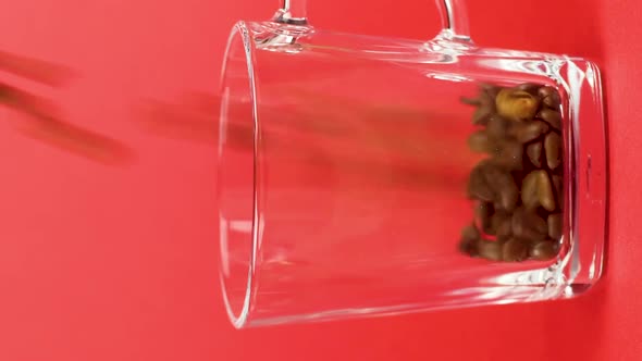 Vertical Video Coffee Beans Quickly Pour Transparent Glass Mug Red Background