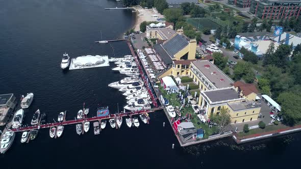 Exciting Aerial View of Marina with Moored Yachts and Pier with Walking People on It alt