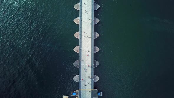 Overhead dolly-in aerial view of the Queen Emma Bridge in St. Anne's Bay, people passing over it, Wi alt