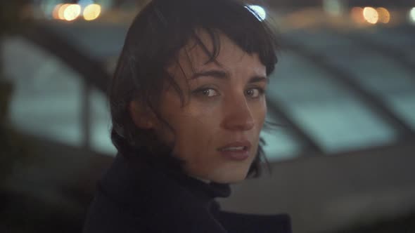 Melancholic Emotive Caucasian Female Walking Staring Back In The City At Night While It Rains alt