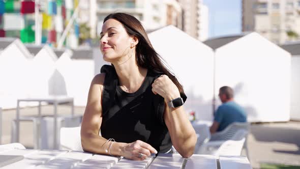 Cheerful Woman Sitting at Outdoor Cafe Table