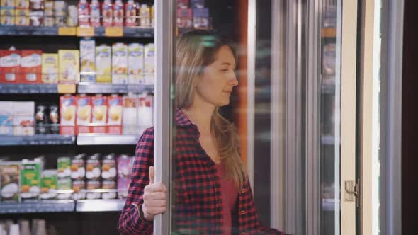 Young American Woman Having Shopping Time at Refrigerated Section in Supermarket.