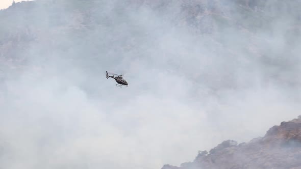 Helicopter flying over wildfire to see the progress of the firefighters ...