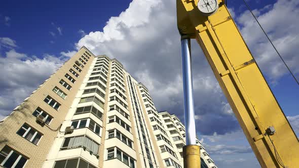 Part of a construction machine (excavator or crane) with multi-storey building under construction