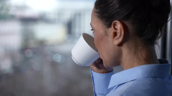 Smiling Face of Woman Drinking Coffee By Window alt