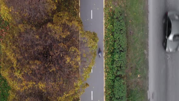 Aerial view Child riding bicycle in autumn park. Active sport family leisur alt