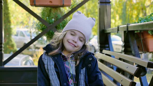 Little Kid Girl Sitting on an Autumn Terrace