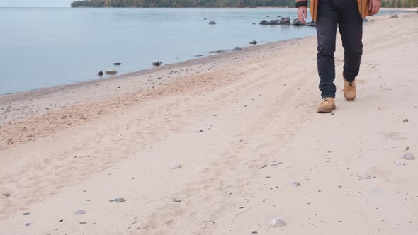 Caucasian Man Walking Along Lake on Sand Beach