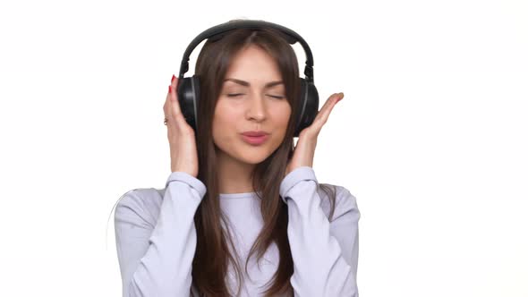 Cute Smiling Caucasian Brunette Female Listening Music with Great Pleasure Through Headphones Over alt