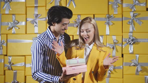 A Charming Couple Poses in Front of the Camera with Gift Boxes in Their Hands