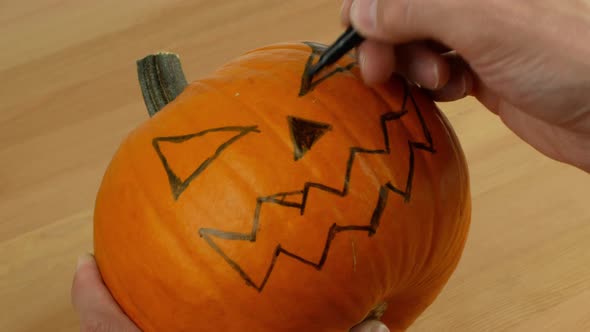 A man carves out a festive Halloween decor with his own hands. Scary pumpkin for Halloween