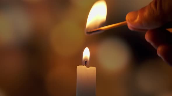 Footage of Using a Match Light a Candle on on a of Colored Blurred Bokeh alt