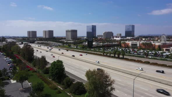 Cars Driving Freeway Irvine High rise buildings city California. Aerial orbit ascending alt