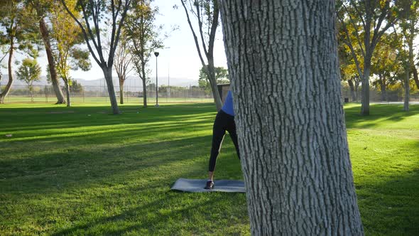 A pretty young hispanic woman stretching and loosening up her body before a workout in the park at s alt