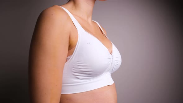Close Up of Female Turning Around Wearing White Surgical Bra Post Breast Augmentation. alt