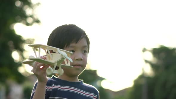 Cute Asian Child Playing Wooden Airplane In The Park Outdoors alt