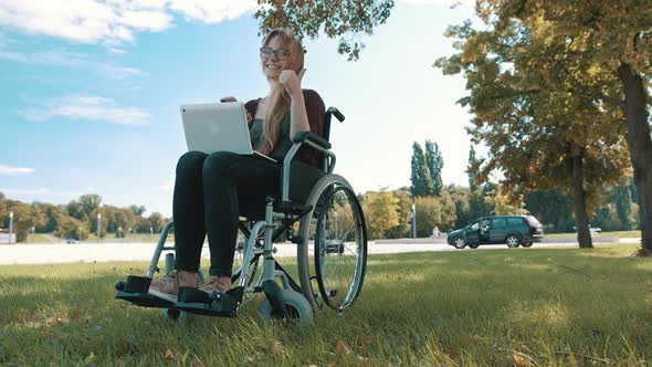 Thumbs Up, Remote Work Concept. Young Disabled Woman in the Wheelchair Using Smartphone and Laptop alt