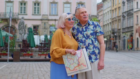 Elderly Stylish Tourists Man Woman Enjoying Conversation on Street Holding Paper Map in Old Town alt