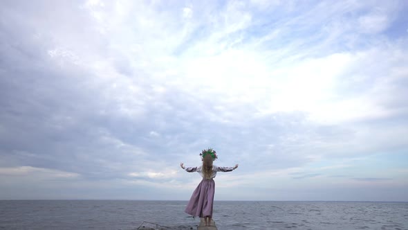 Extreme Wide Shot of Young Ukrainian Woman Standing on River Bank Raising Hands to Cloudy Sky in alt