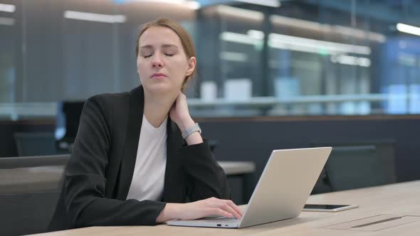 Businesswoman Having Neck Pain While Typing on Laptop alt