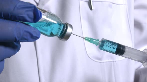 Medical analyst injects a glass vial with blue liquid into a syring alt