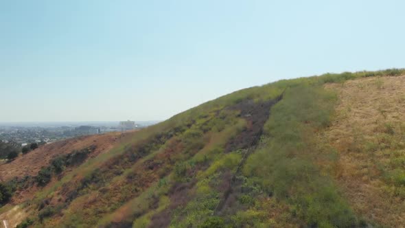 Los Angeles Downtown City Skyline Reveal Drone Shot over Green Hillside